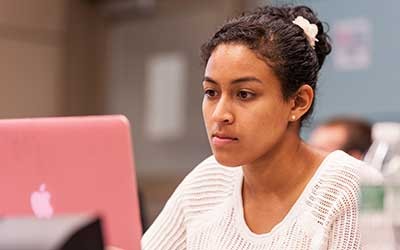 Student in front of a pink laptop