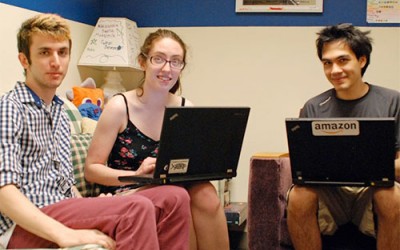 Three students sitting in chairs with laptops