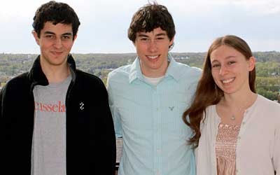 Three students outside with landscape behind them