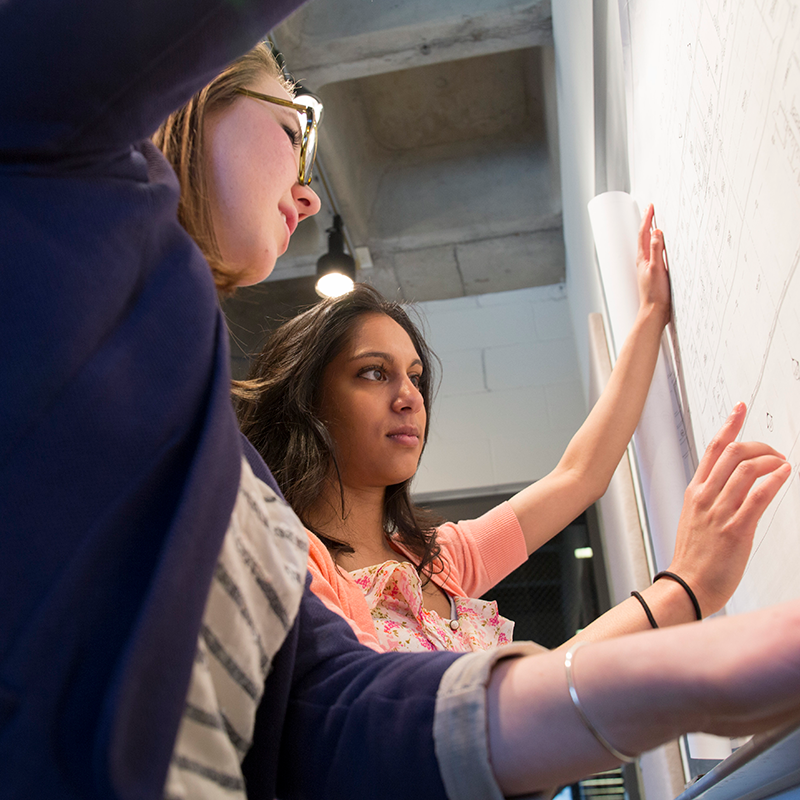 Two students work at a whiteboard